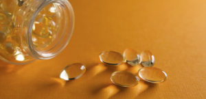 Bottle of Vitamin D Capsules on its side with capsules spilling out onto a yellow surface