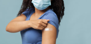 woman showing arm with adhesive medical bandage after covid-19 vaccine injection.